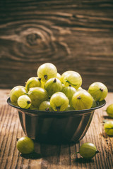 Gooseberries in a metal bowl on wooden background