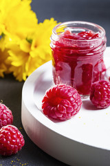 Mini jar of raspberry jam on a white ceramic plate