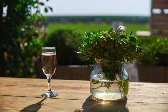 Glass with champagne on a wooden table, Sunny day.