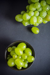 White grapes in bowl and bunch of them on stone kitchen table