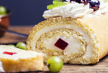 Cream roll cake on wooden background, closeup