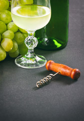 WIne glass, corkscrew and fresh grapes closeup