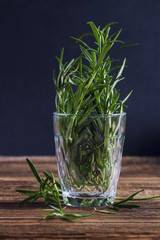 Rosemary in a glass on a wooden table