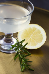Alcoholic drink with rosemary and lemon on golden background