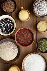 Cereals and legumes in bowls on wooden background. Top view
