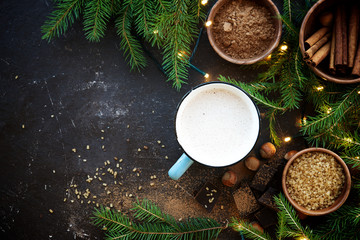 Naklejka na ściany i meble Cocoa with cream and ingredients on dark brown wooden background. Decoration with spruce branches and Christmas garland