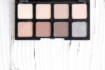 Top view of pink and brown tone make up palette on white wooden background