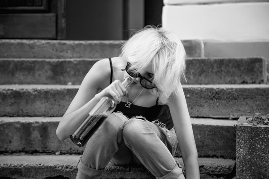 Young female with alcoholic drink looking very sad and depressed. Alcoholism in young adults (alcoholism, pain, pity, hopelessness, social problem of dependence concept)