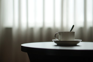 Fototapeta na wymiar white coffee cup on the table by a sofa couch in hotel room