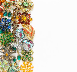 Woman's Jewelry. Vintage jewelry background. Beautiful bright rhinestone brooches, braceletes, necklace and earrings on white. Flat lay, top view