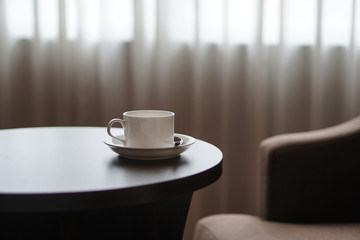 white coffee cup on the table by a sofa couch in hotel room
