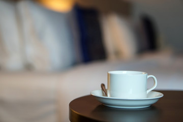 white coffee cup on the table by a sofa couch in hotel room