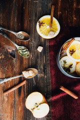 Mulled wine in rustic mug with spices and ingredients on wooden background. Top view, flat lay. Retro toned photo. Copy space for your text.