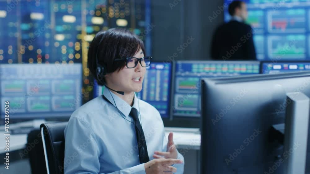 Fototapete In the Network Operations Center Trader Makes Personal Client Call with a Headset. He's Surrounded by Monitors Showing Stocks Data and Graphs. Shot on RED EPIC-W 8K Helium Cinema Camera.
