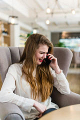 Beautiful young girl with professional makeup and hairstyle sitting in restaurant.