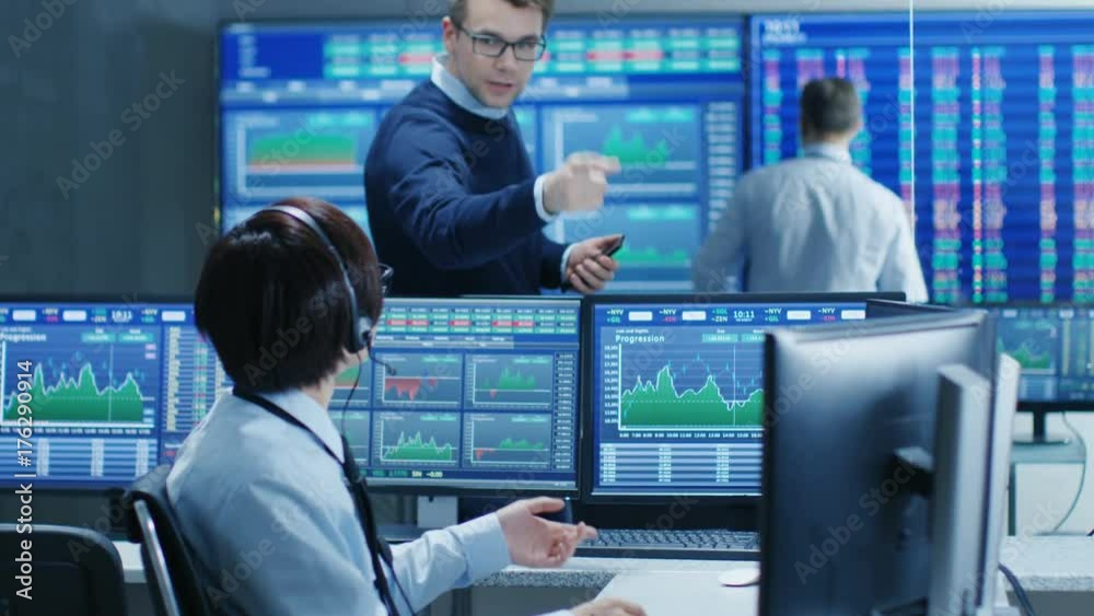 Fototapete In the Network Operations Senior Trader Dictates Stock Numbers to Their Operator who Makes Call with a Headset. In the Background Traders Discuss Data Shown on Monitors. 