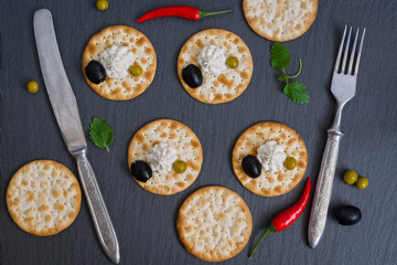 Crackers with cheese and red fish on a plate of slate.