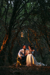 happy couple sitting on bench near camp fire