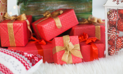 Closeup view of many boxes wrapped in red festive wrapping paper. Festive presents  under holiday Christmas tree. Horizontal color photography.