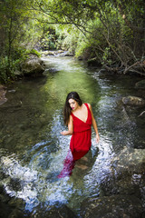 Fototapeta premium Beautiful woman on the bank of a mountain river with an evening dress
