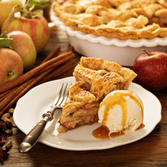 Piece of an apple pie with ice cream on a plate