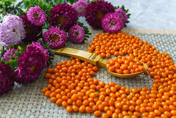 a handful of scattered sea-buckthorn and a bouquet of lilac asters on the table.