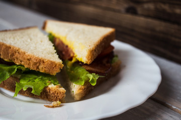 sandwich with bacon and salad on a wooden background