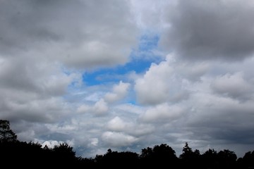A mix of white and gray clouds in a patchy blue sky. 