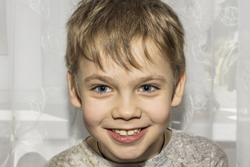 A boy is looking at you while smiling.