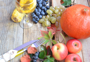 Autumn place setting. Thanksgiving dinner. Fall season fruit, pumpkins, plates, wine and candles. Thanksgiving dinner