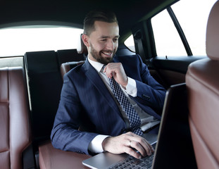 businessman reads information on laptop while sitting in car
