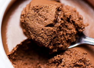 Chocolate Mousse in White Cup Bowl. Spoonful Visible  Spongy Texture with Pores. Vibrant Rich Brown...