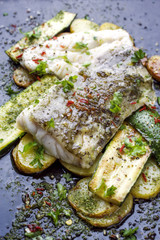 Fried cod fish fillet with vegetable and potatoes as top-view on old board