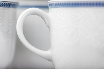 Set of clean white cups located on the shelf