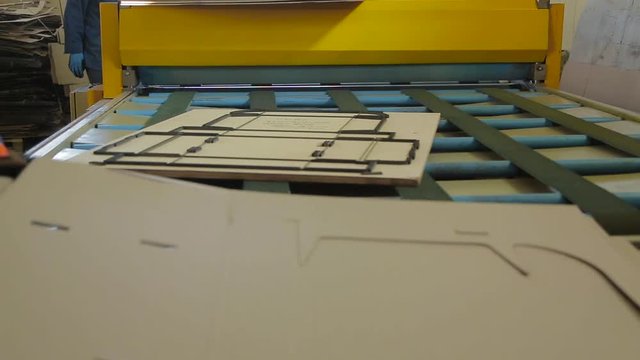 Carving of a cardboard box by means of a mold under a press. Cutting machine. Close up box die cutting mold on manufacture of cardboard boxes