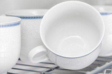 Set of clean white cups located on the shelf