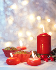 Close up of muffins in a red wrapper with red candles and holiday wreath. Bokeh background with a shallow depth of field