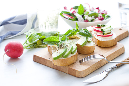 Bruschettas with cream cheese,  radish, avocado and basil. Close up
