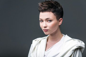 Portrait of a young beautiful girl wearing in white against a dark background. A girl with a short haircut