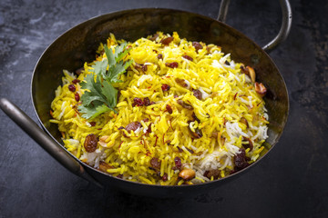 Indian vegetarian biryani with nuts and raisins as close-up in a korai