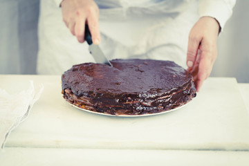 Woman slicing into a chocolate layer cake