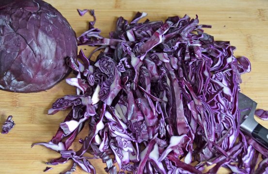 closeup of red cabbage sliced with a knife and cutting board 