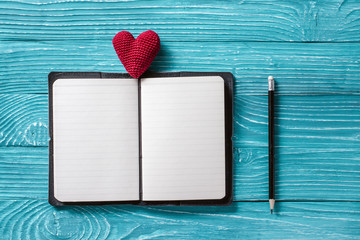 Blank notepad for copy space and vintage handmaded valentines day toy heart over light blue wooden...