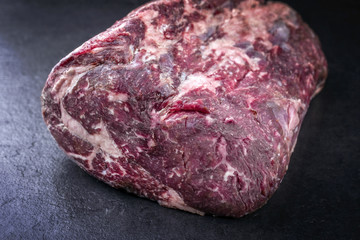 Raw dry aged Kobe rib eye steak as close-up on a black board