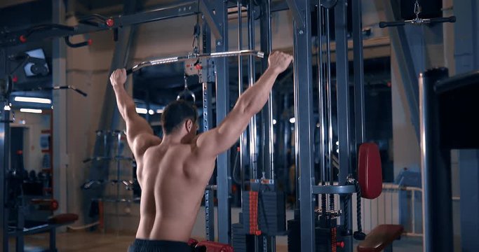 bodybuilder doing exercise on the simulator in the gym. exercises for muscles of a back