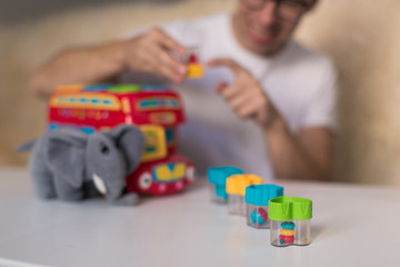 Close-up toys on the table with which young man playing indoors