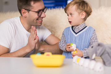 The young happy father playing of toys with his little cute son indoors and they looking at each other