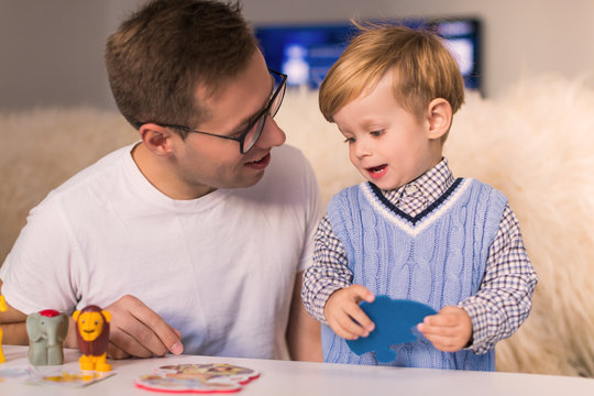 Portrait of young happy father with little cute son making pazzles at home
