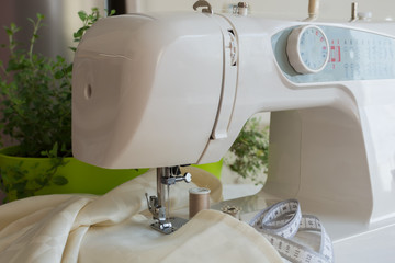 Sewing machine sews ecru color  fabric, sewing accessories around