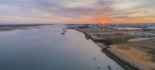Sunrise aerial panoramic seascape view of Olhao dockyard, waterfront to Ria Formosa natural park with Armona island in background. Algarve.